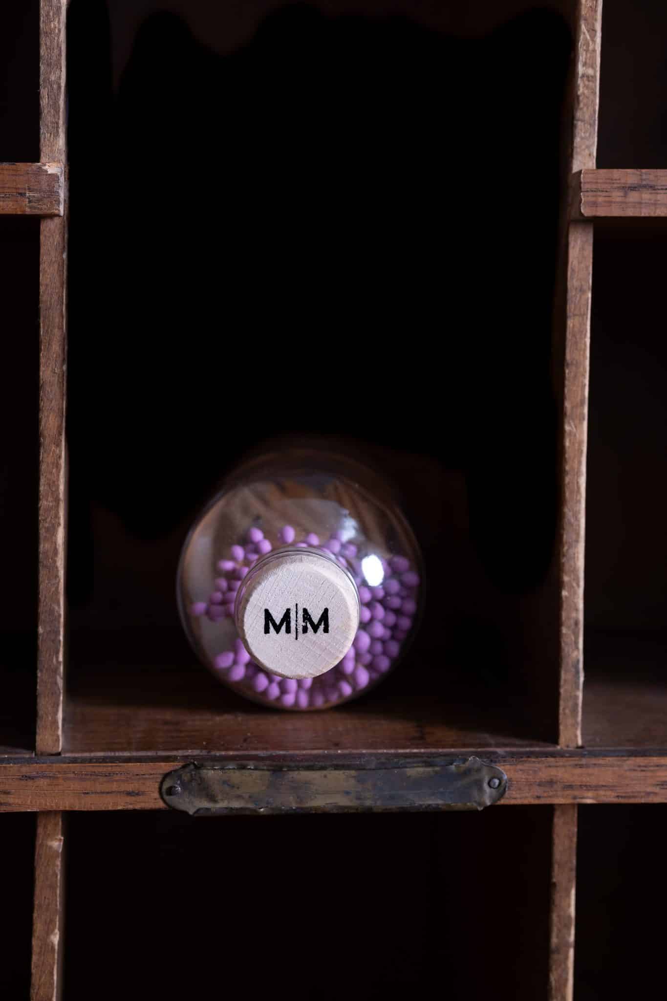 Top view of the wooden cork lid on a Vintage Apothecary Fuchsia Matches jar, featuring the "MM" branding and a peek at the vibrant fuchsia matchsticks inside.