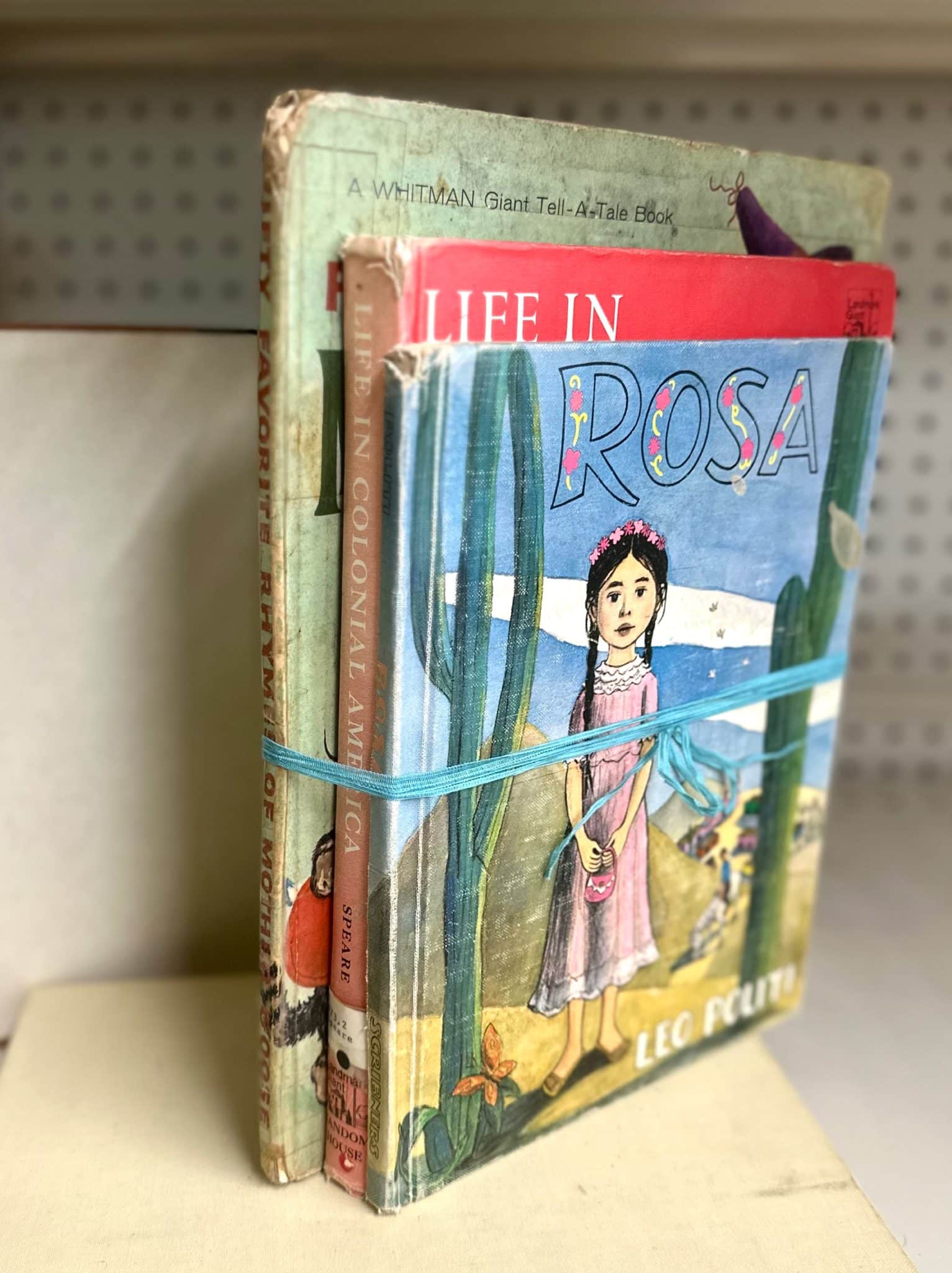 Trio of vintage hardcover books with eclectic covers tied in ribbon