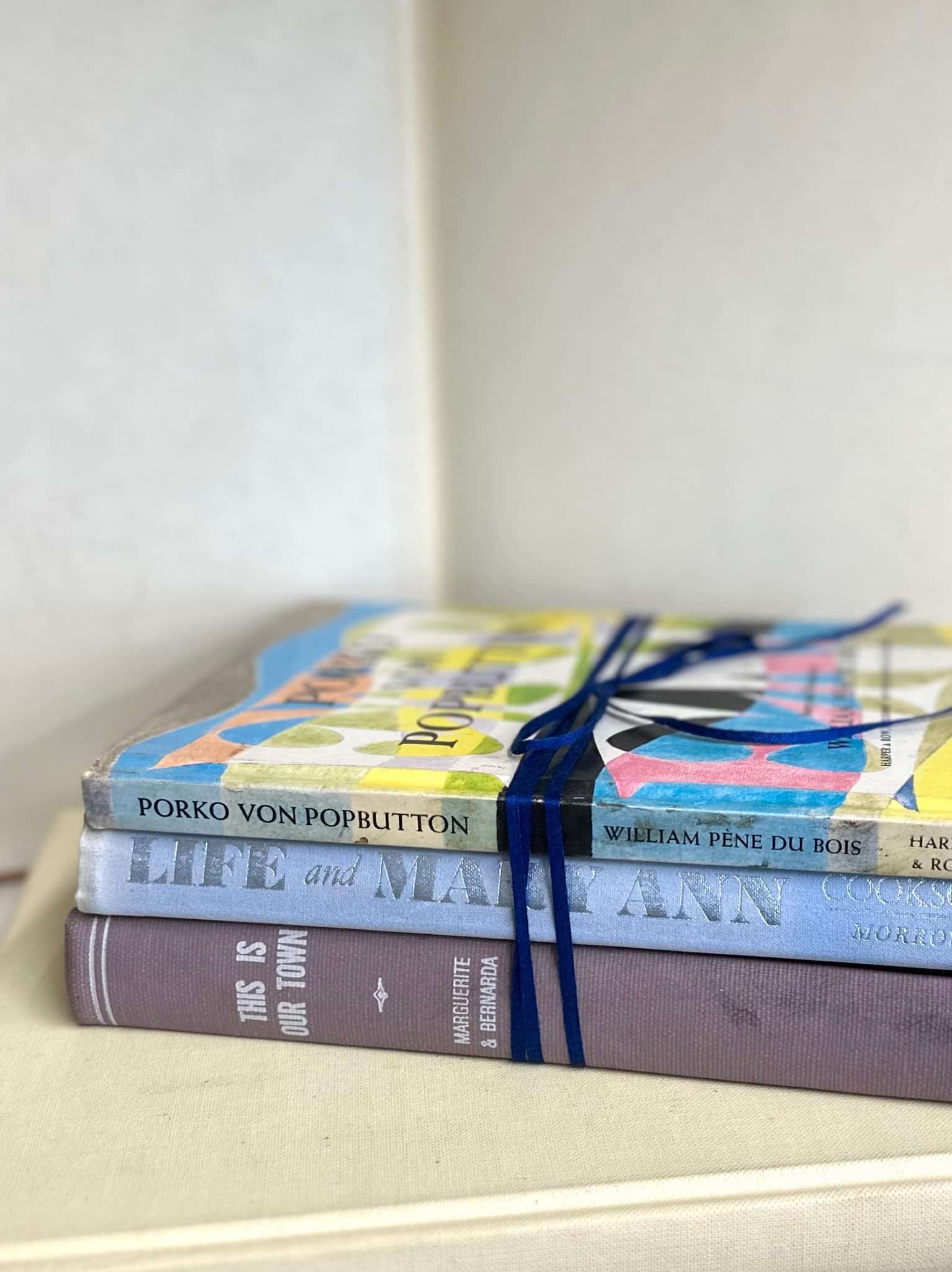 Colorful vintage hardback books tied with navy ribbon in a stacked display