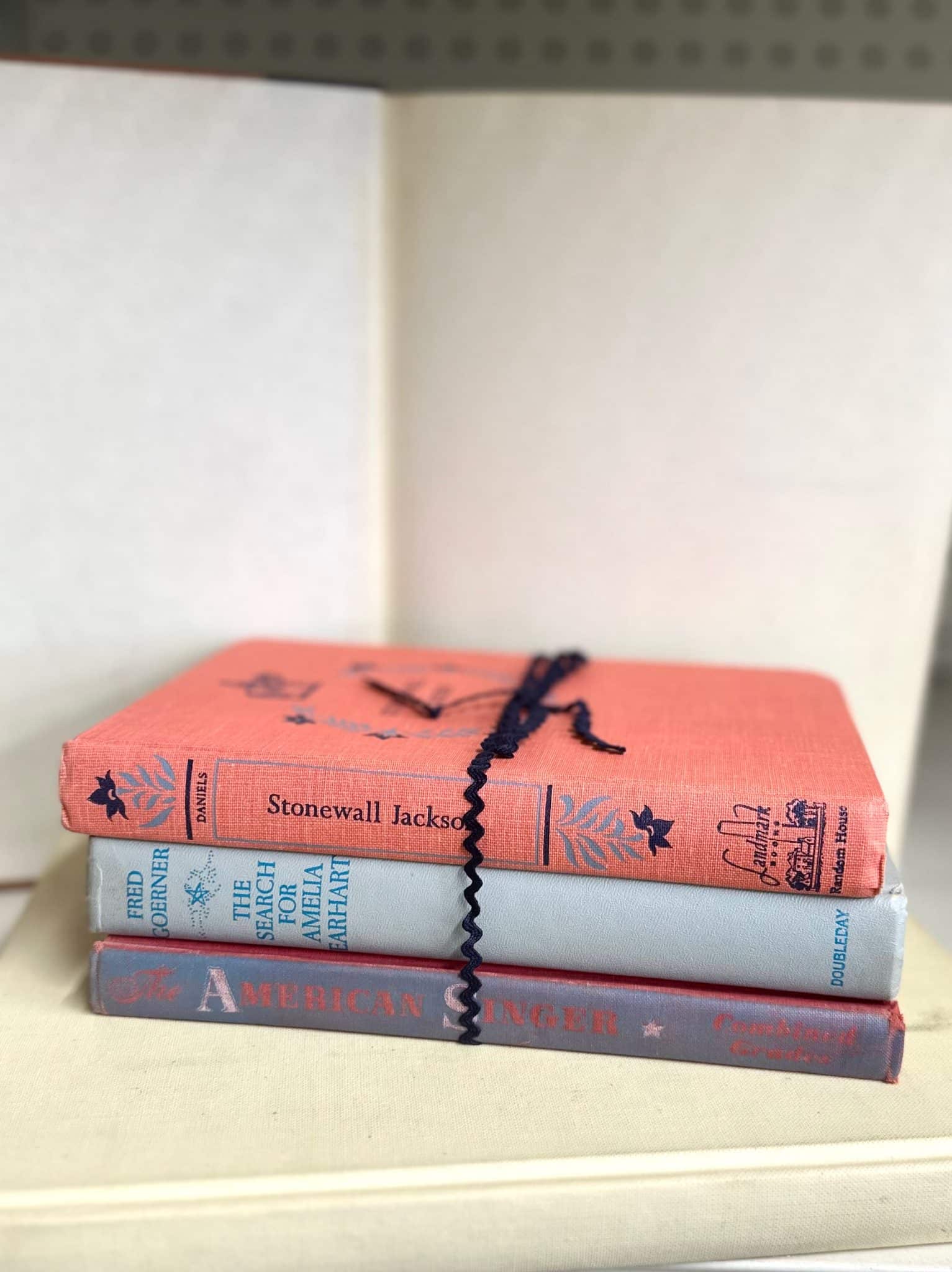 Stack of three decorative vintage books with mixed colors and aged covers