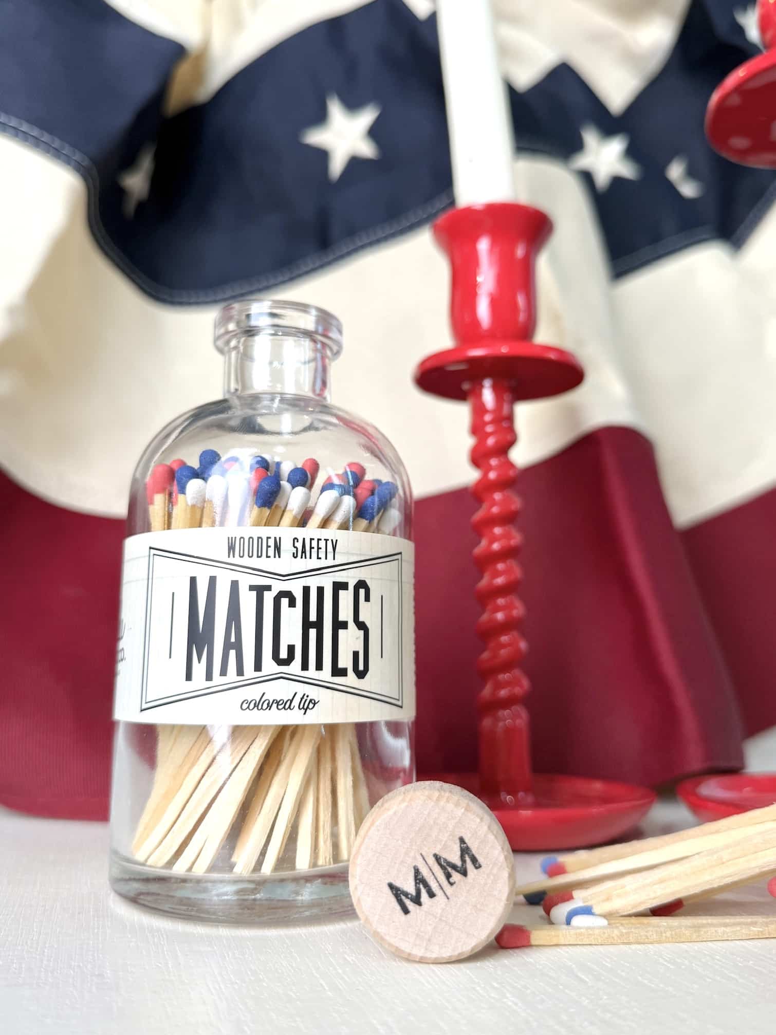 Vintage Apothecary USA Match jar displayed with red taper candle holders and scattered tri-color matchsticks in a patriotic decor scene.