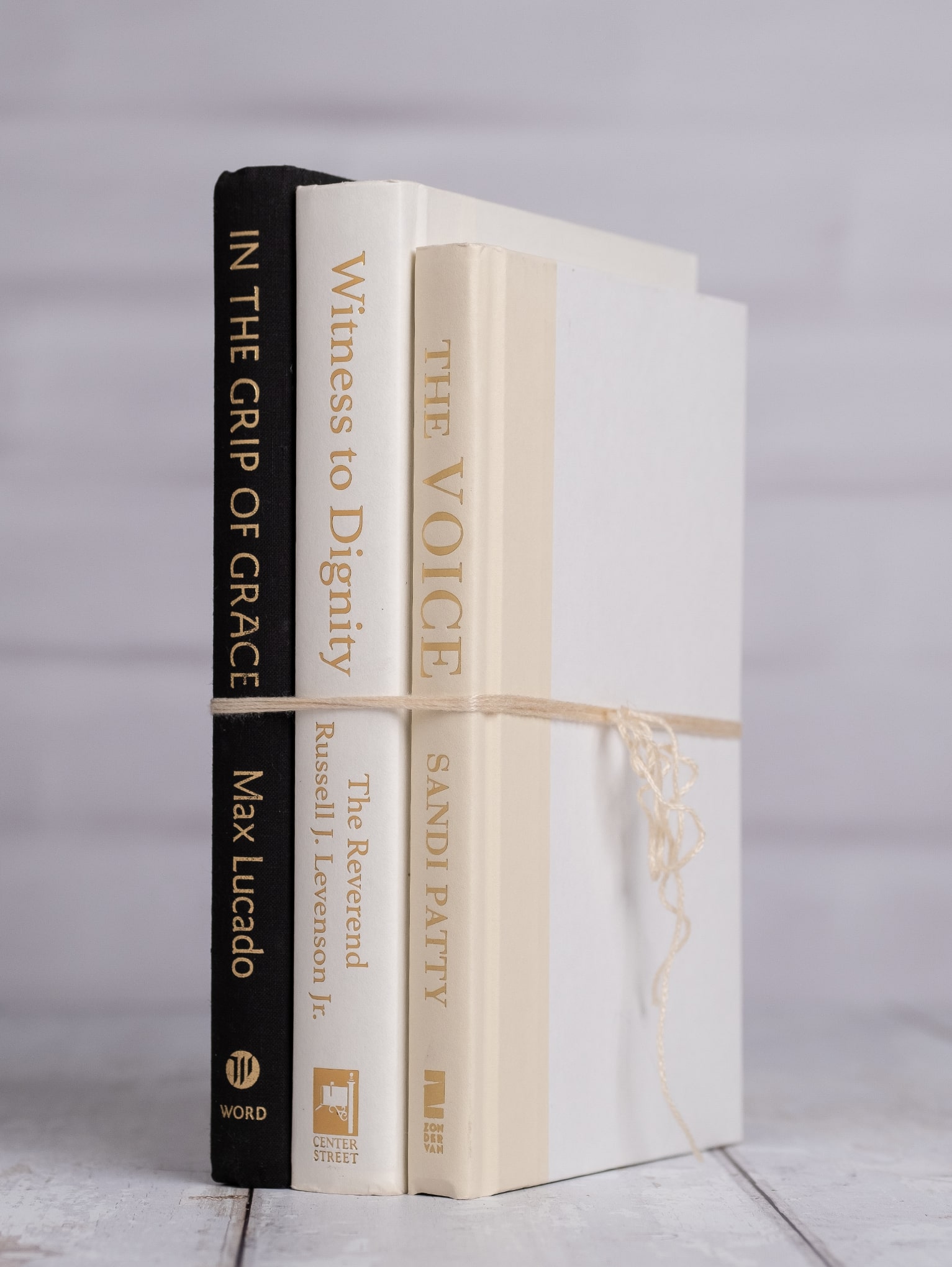 Trio of pre-loved books with black, cream, and tan covers, wrapped in twine.