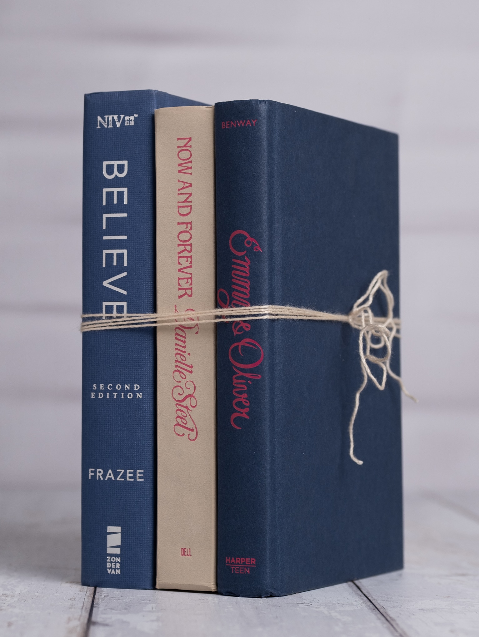 Side angle of a navy and cream book trio with pink and white lettering tied with white twine.