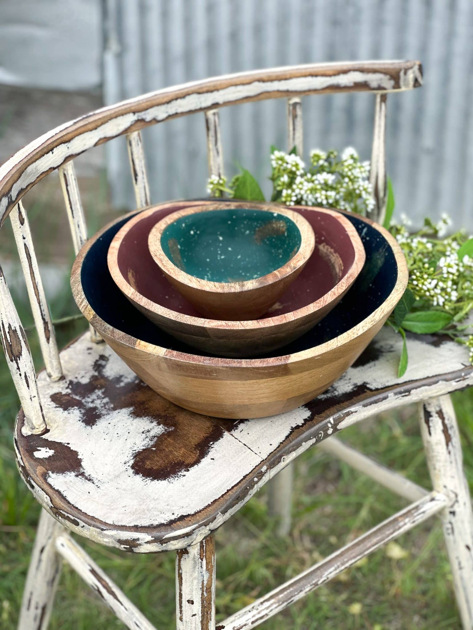 Set of three stacked wood melamine bowls in blue, mauve, and teal with splatter patterns