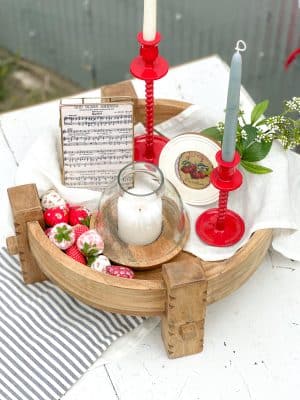 Top-down view of a Wood Chakki Table styled with patriotic strawberries, red taper holders, and a hurricane candle holder.