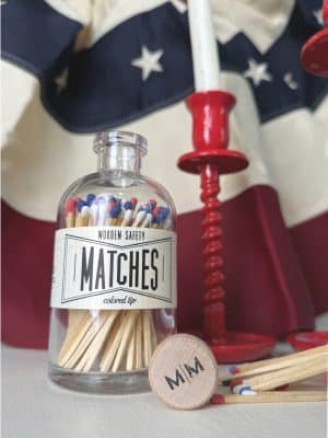 Vintage Apothecary USA Match jar displayed with red taper candle holders and scattered tri-color matchsticks in a patriotic decor scene.