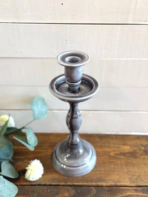 Top-down angled view of a single medium gray taper candle holder showing the pooled enamel finish.