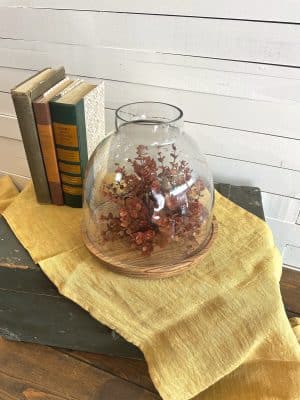Glass cloche-style hurricane on mango wood base styled with dried florals and vintage books