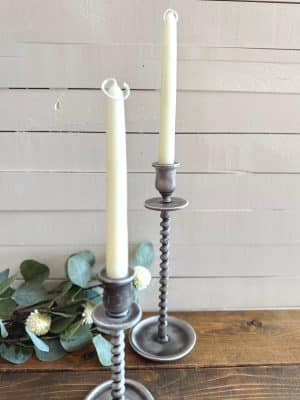 Two gray corkscrew taper candle holders styled with tall ivory taper candles and eucalyptus greenery.