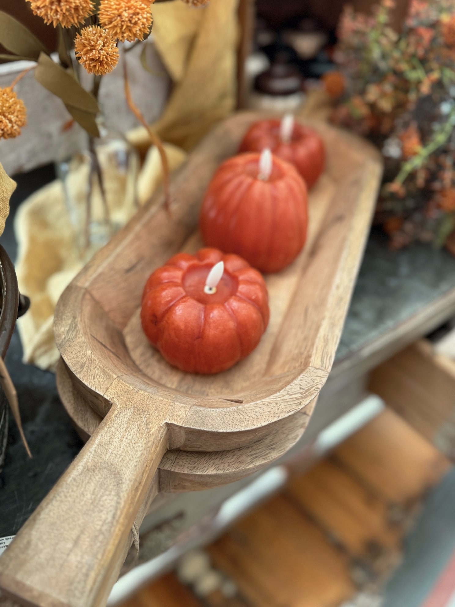 Rustic wood dough bowl with sturdy handles, displayed as a fall centerpiece with pumpkins and florals.