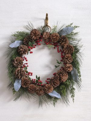 Holiday wreath featuring pinecones, red berry clusters, wispy greenery, and muted blue leaves arranged around a 10-inch inner ring.