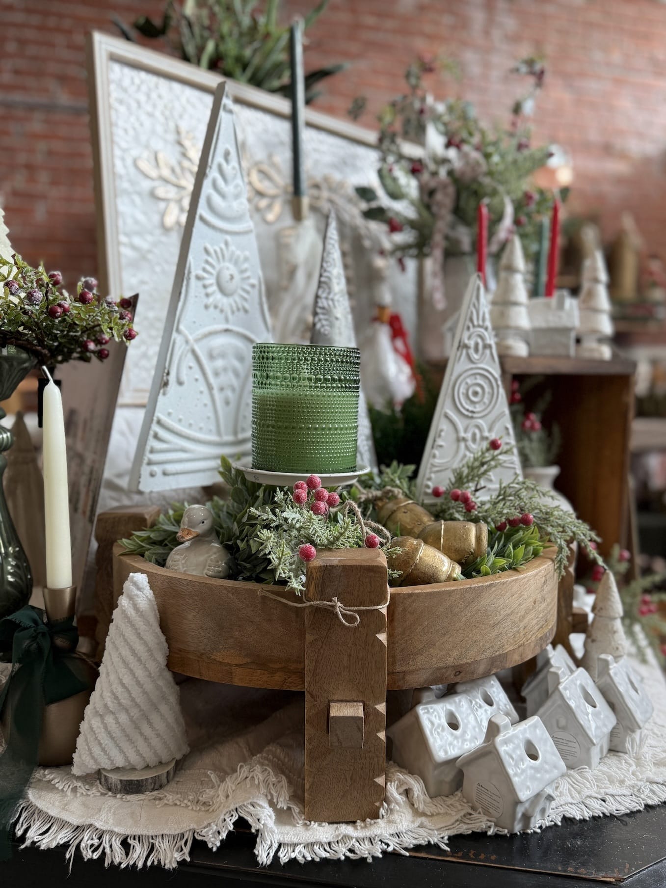 Wood Chakki Table Pedestal styled with embossed metal trees, a green hobnail candle, faux greenery, and vintage brass bells.