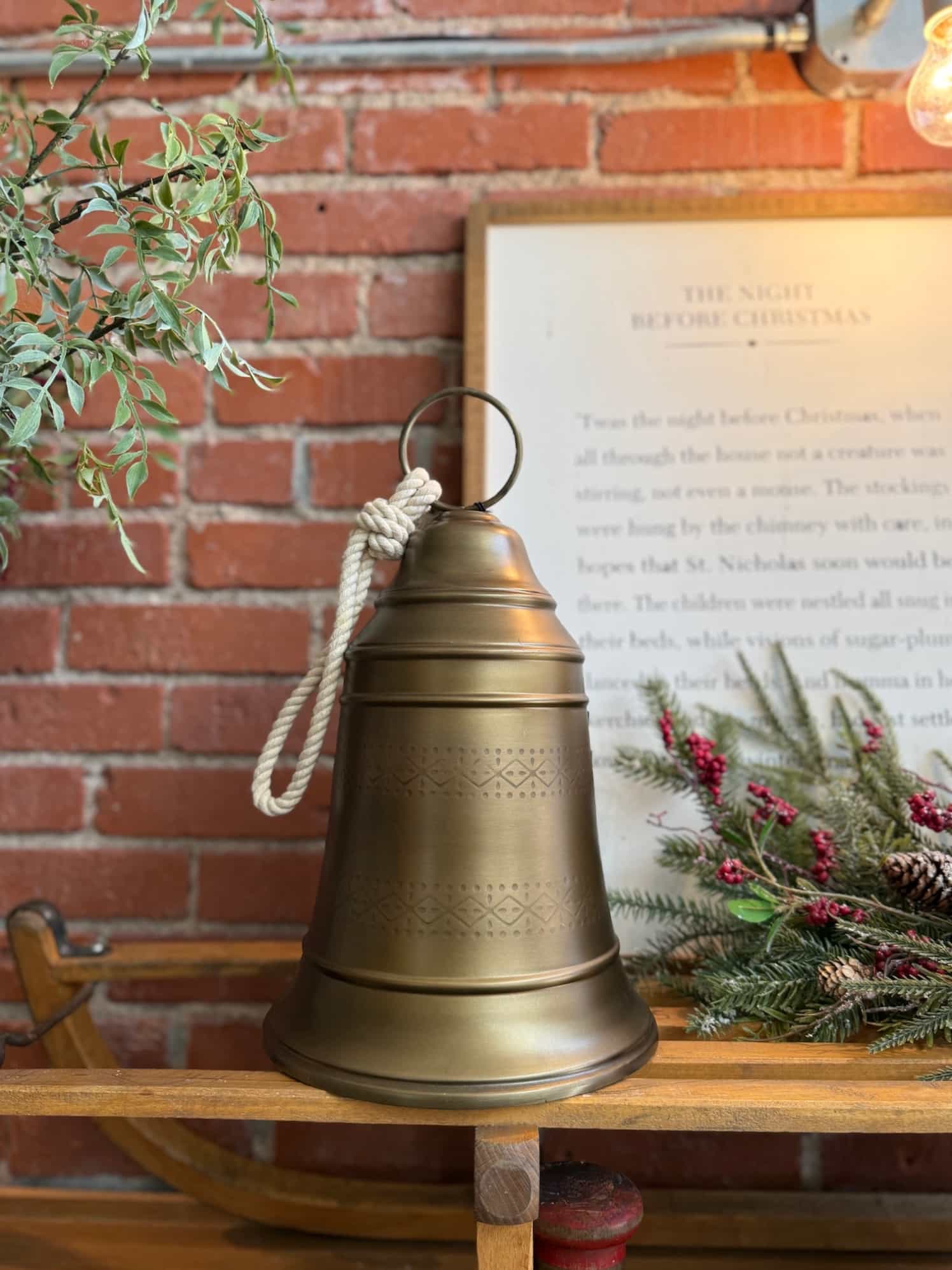 made-market-co-hays-ks-antique-brass-bell-medium Antique Brass Bell Medium styled on a rustic wooden bench with a braided rope hanger.