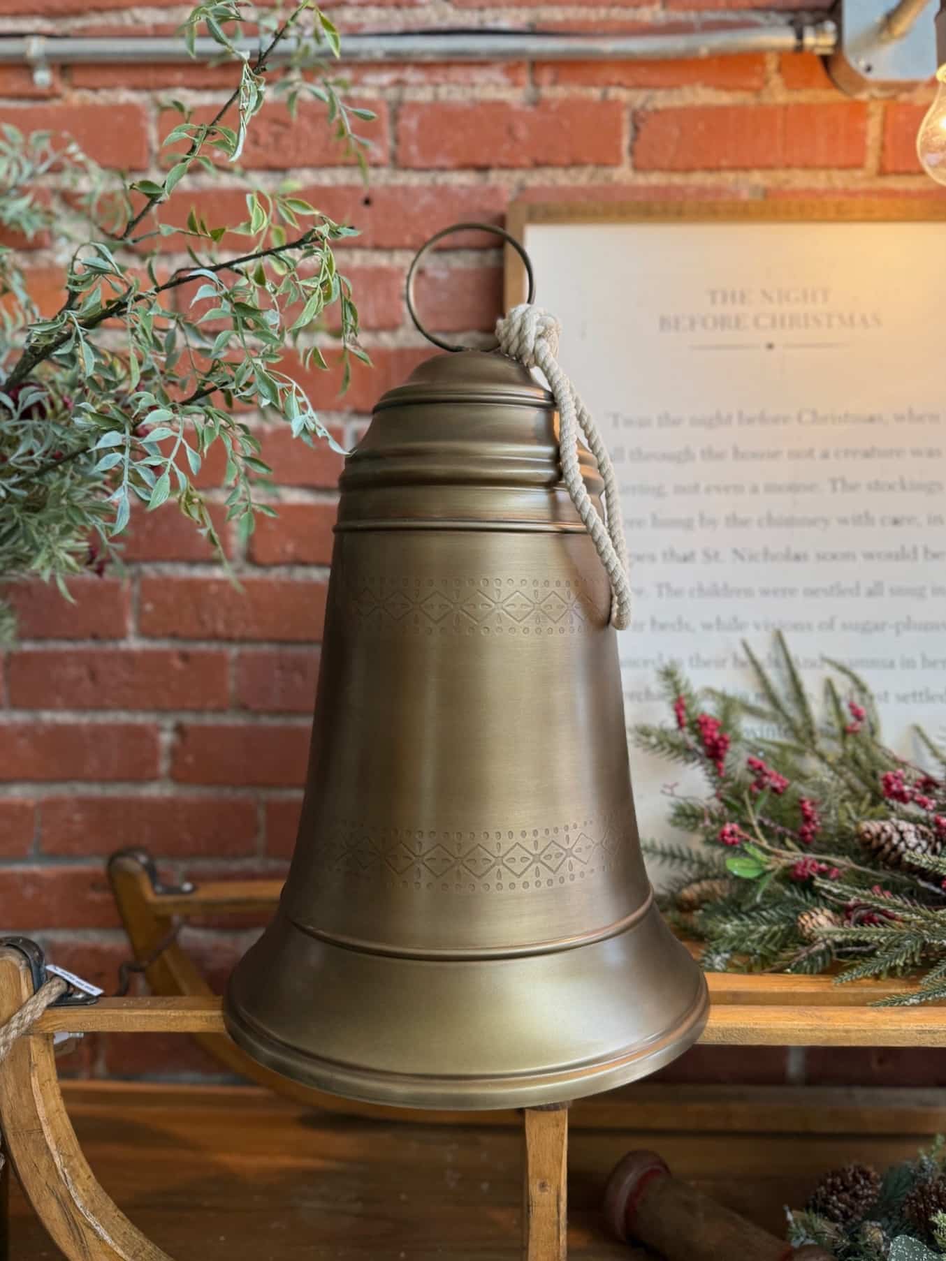 made-market-co-hays-ks-antique-brass-bell-large Antique Brass Bell Large styled on a rustic wooden bench with braided rope hanger.