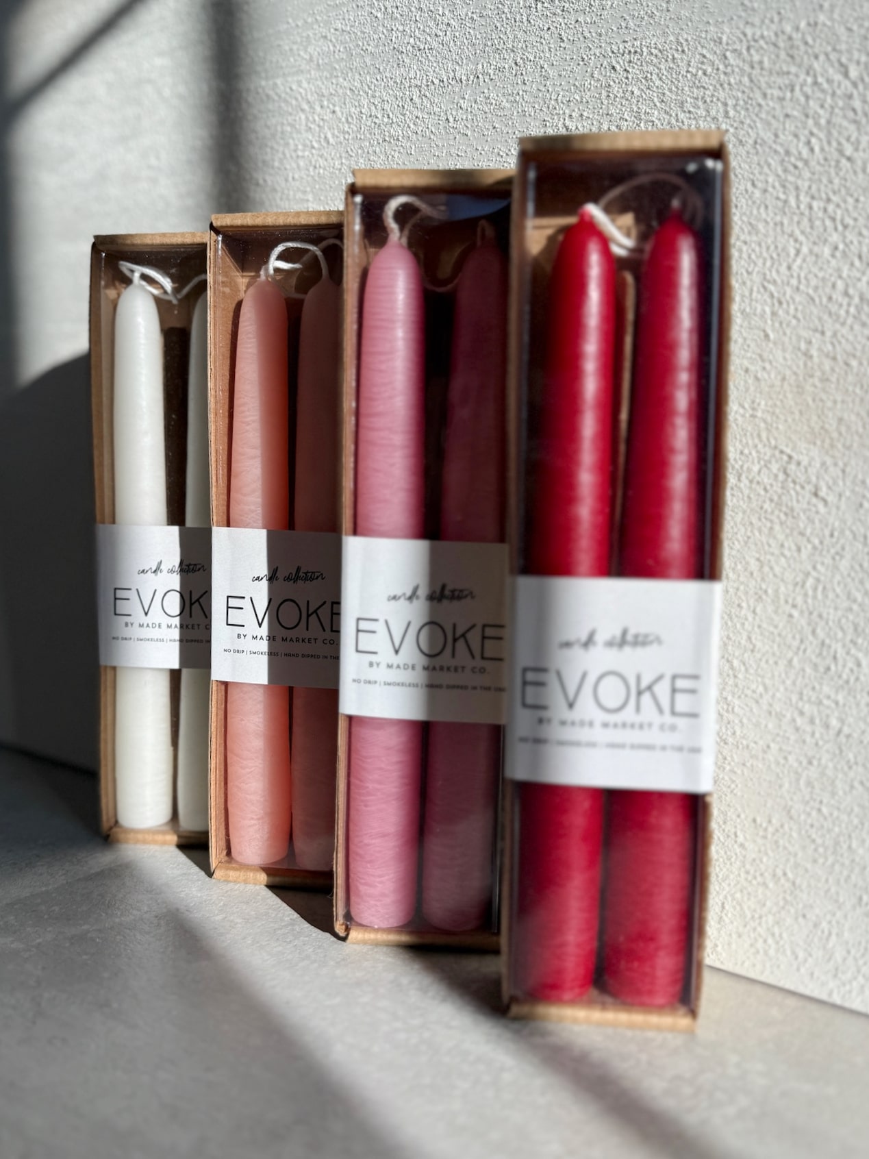 Boxed Our Taper Candles in off white, peach blossom, rosewood, and fiery with evoke labels.
