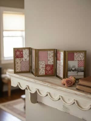 Oversized hinged gold photo frame with five 4x6 panels featuring red patchwork prints and a vintage winter photo, styled on a distressed white shelf with dried roses and stacked books.